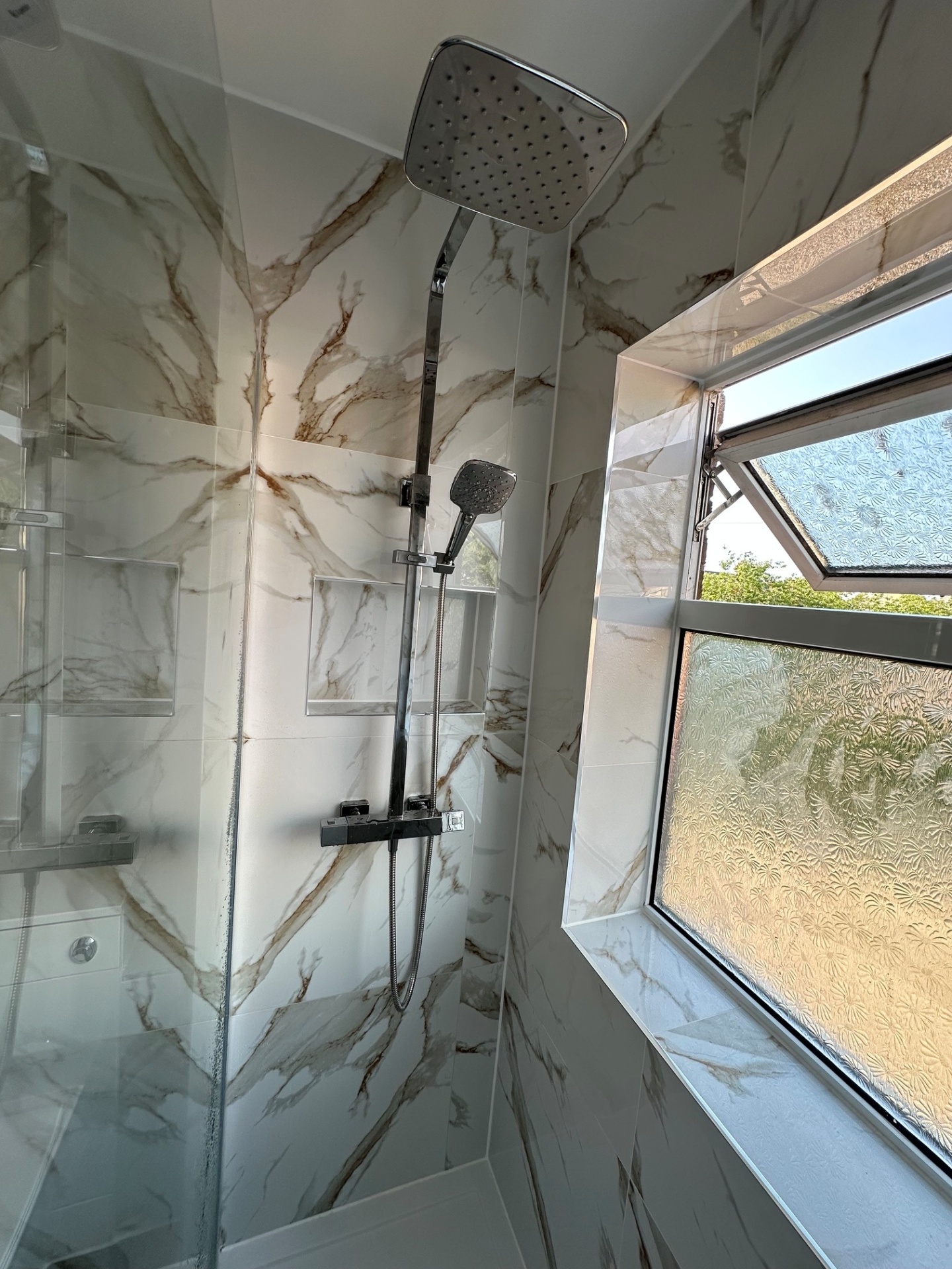 Calacatta marble walk-in shower with chrome thermostatic riser