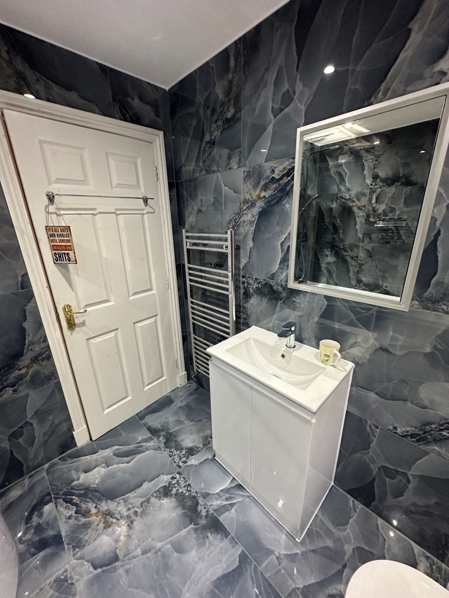 Dramatic black marble cloakroom with chrome heated towel rail